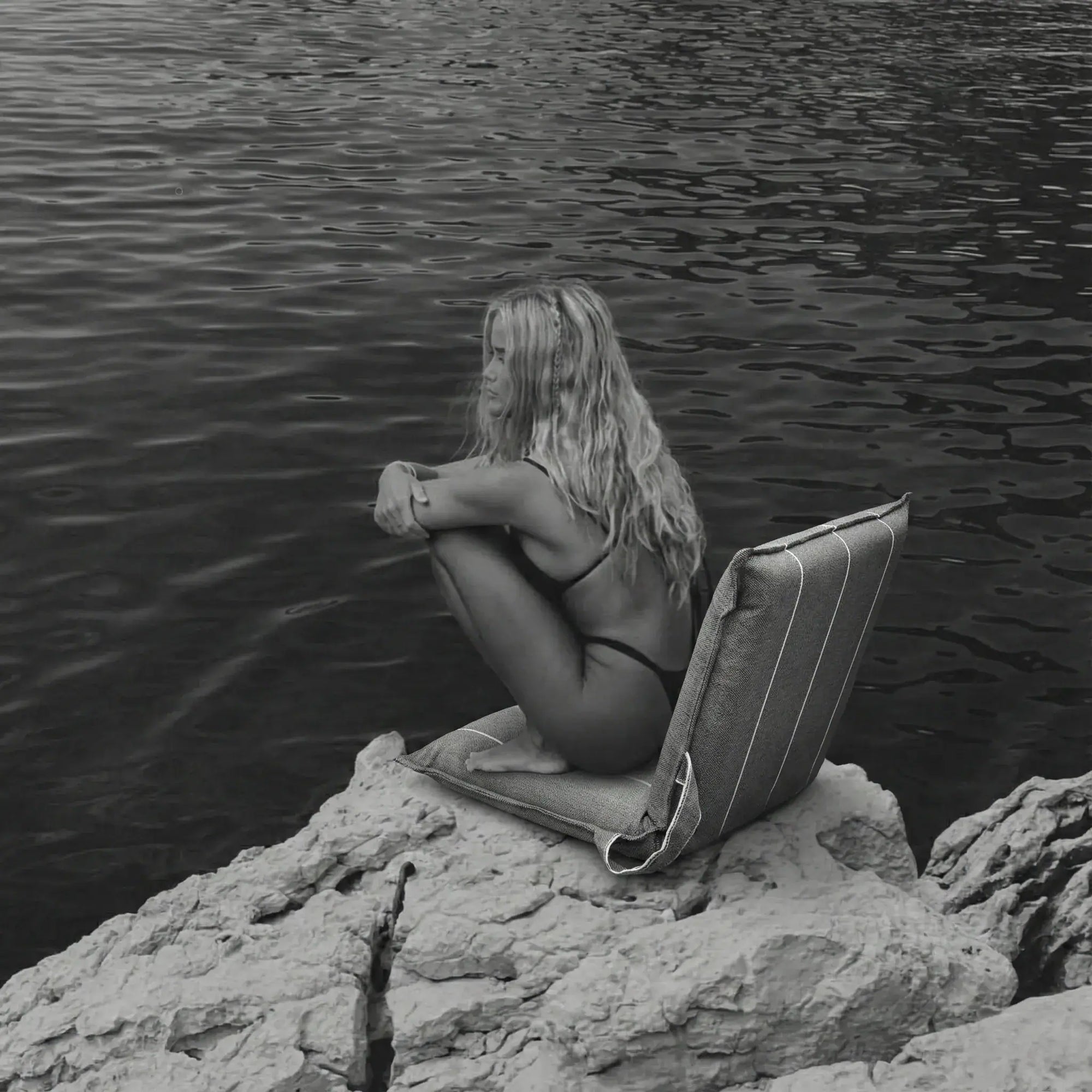 Woman relaxing on a La Chaise portable reclining beach lounger on coastal rocks
